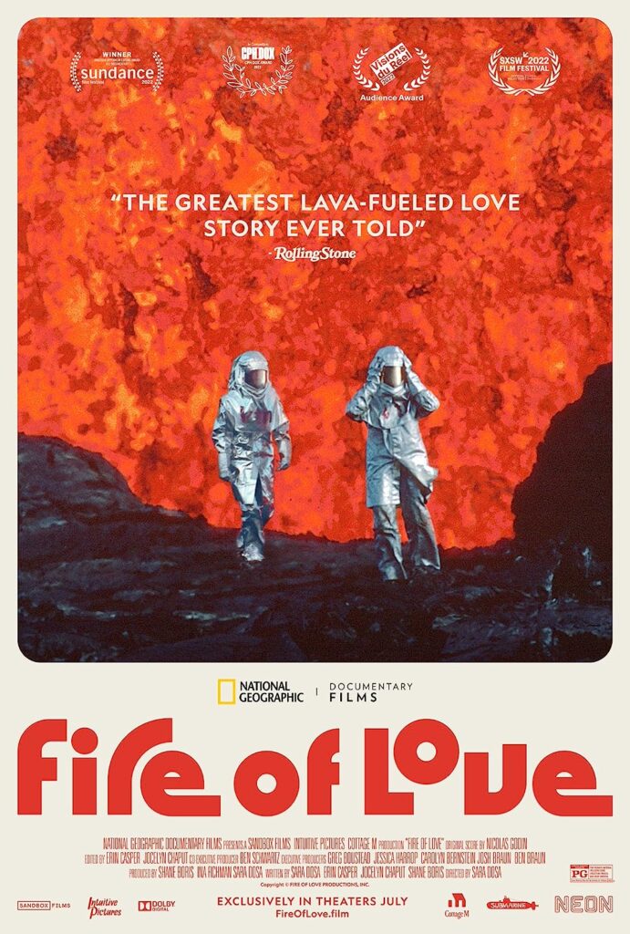 The official movie poster for 'Fire of Love' (2022), depicting Maurice Krafft and Katia Krafft wearing protective equipment and in front of a fountain of lava.